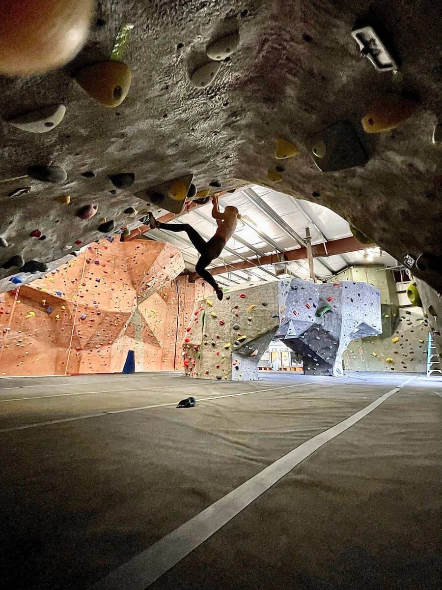 Young climber on the overhanging bouldering wall