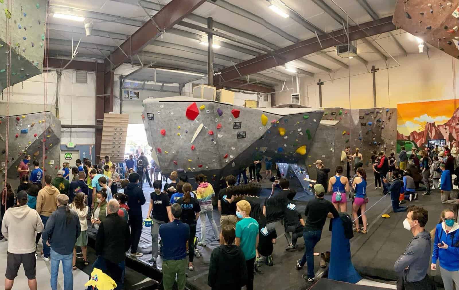 Crowd gathered at the bouldering wall during a gym event