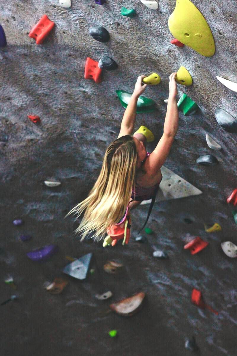 Young climber reaching for a hold on the bouldering wall